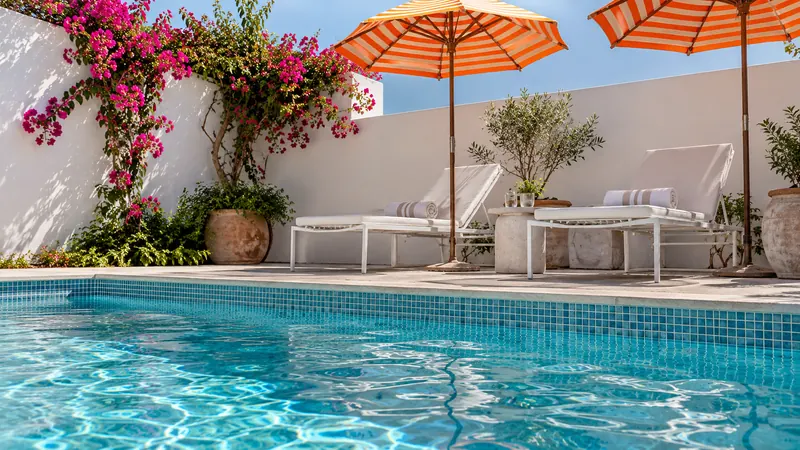 Blue swimming pool with orange-striped umbrellas