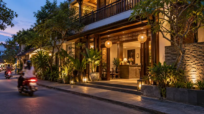Hotel entrance at dusk with passing scooters